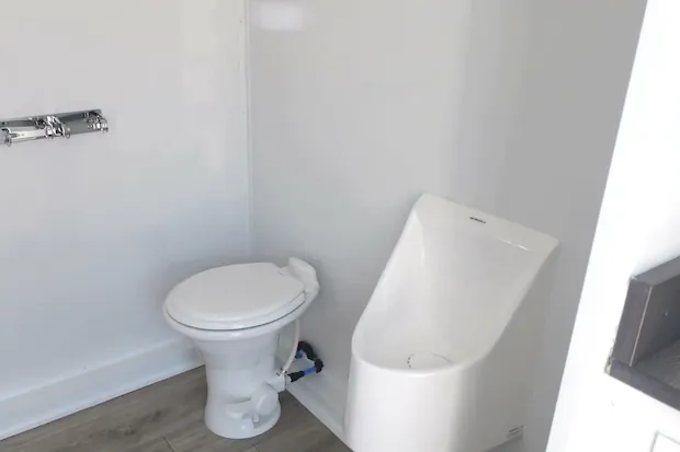 The men's restroom with a white china toilet and a waterless urinal